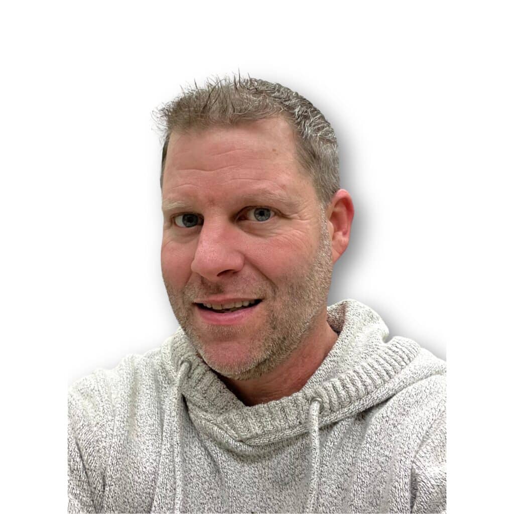 Man with short hair wearing a light gray hoodie, smiling at the camera against a plain background.