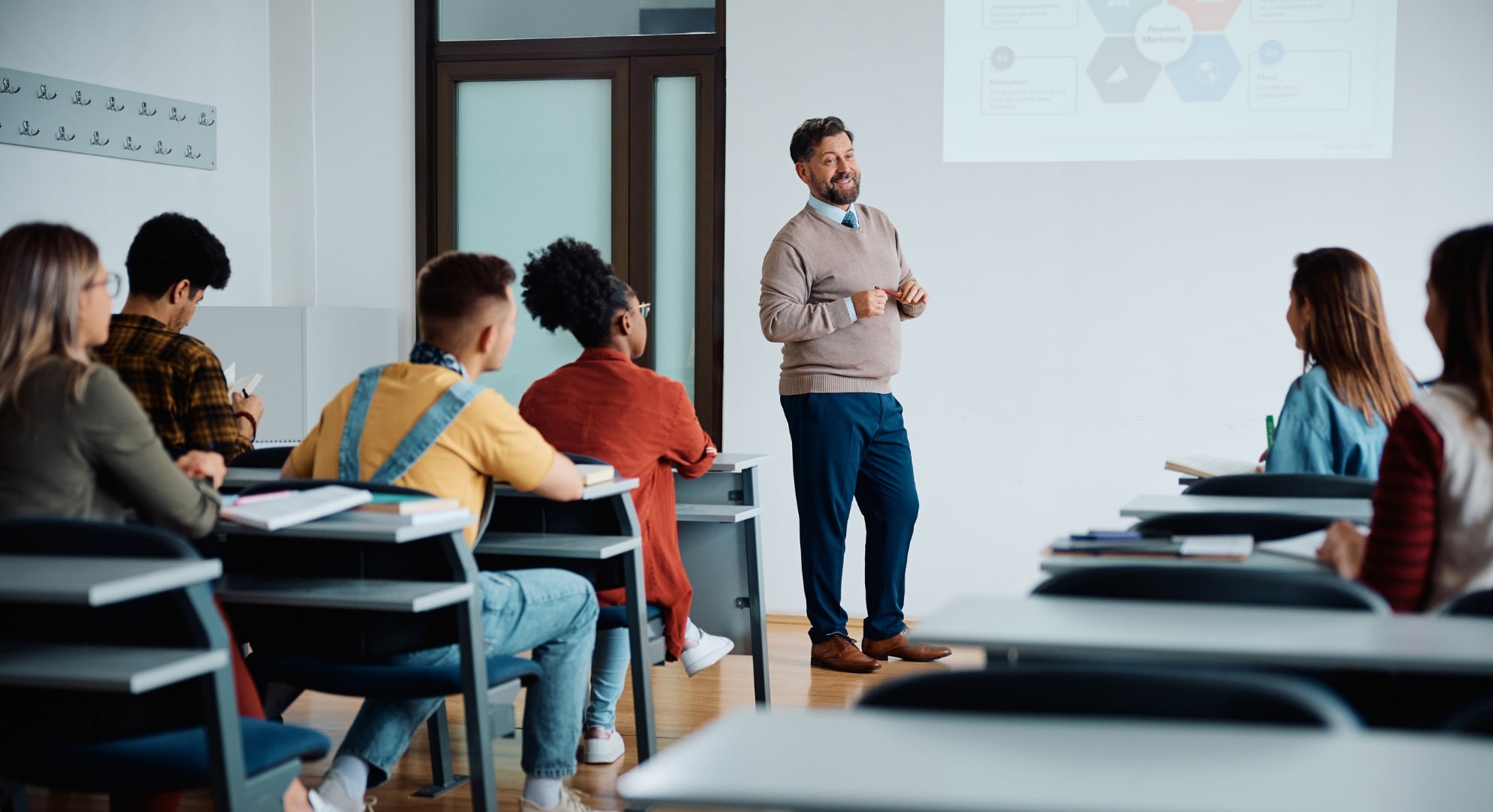 A teacher presents a slide to a classroom of students, who are seated and taking notes, in a modern, well-lit setting equipped with the latest 3D scanning technology.