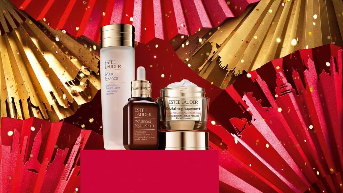 Marketing 8 - 50_50 Estee Lauder skincare products, including a bottle of Micro Essence, Advanced Night Repair serum, and Revitalizing Supreme+ cream, are displayed against a backdrop of red and gold paper fans, showcasing the precision akin to 3D scanning.